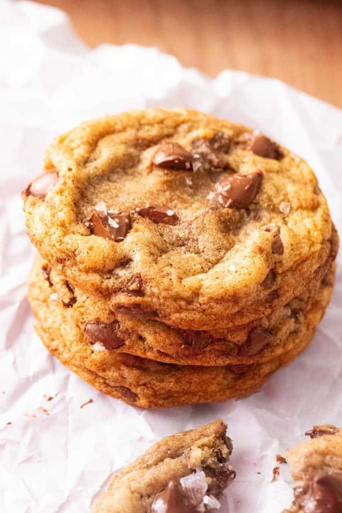 One bowl chocolate chip cookies with flaky sea salt stacked on a board.